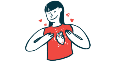 A woman smiles while gesturing to an heart pictured on her shirt.