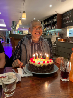 Aubrey in front of a birthday cake lit with candles at a restaurant. 