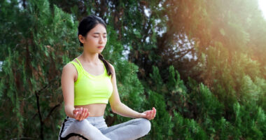 a woman in sportswear practicing meditation while sitting in the lotus position on a wall